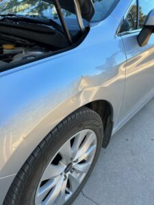 picture of a dent on a fender of a subaru that can have the process of paintless dent repair applied to it