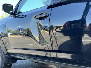 picture of a dent on a door of a toyota that can have the process of paintless dent repair applied to it